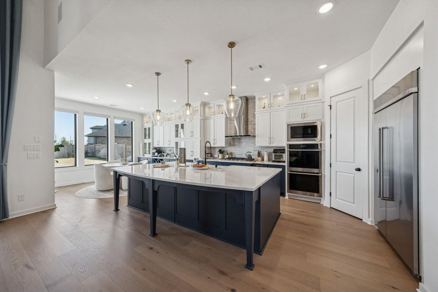 Double ovens and cabinets to the ceiling with class doors and inset lighting.