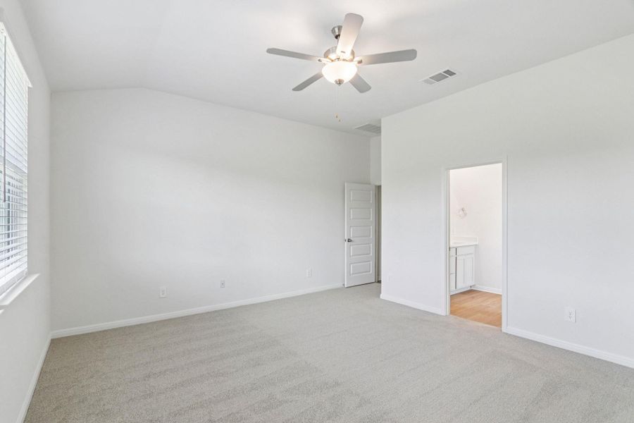 Unfurnished bedroom with lofted ceiling, light colored carpet, ceiling fan, and ensuite bath Unfurnished bedroom with lofted ceiling, light colored carpet, ceiling fan, and ensuite bath