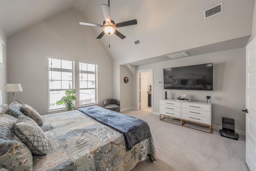 Bedroom with light carpet, ceiling fan, and high vaulted ceiling