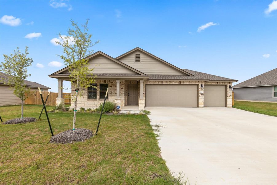 Ranch-style house with a porch, a garage, driveway, roof with shingles, and brick siding