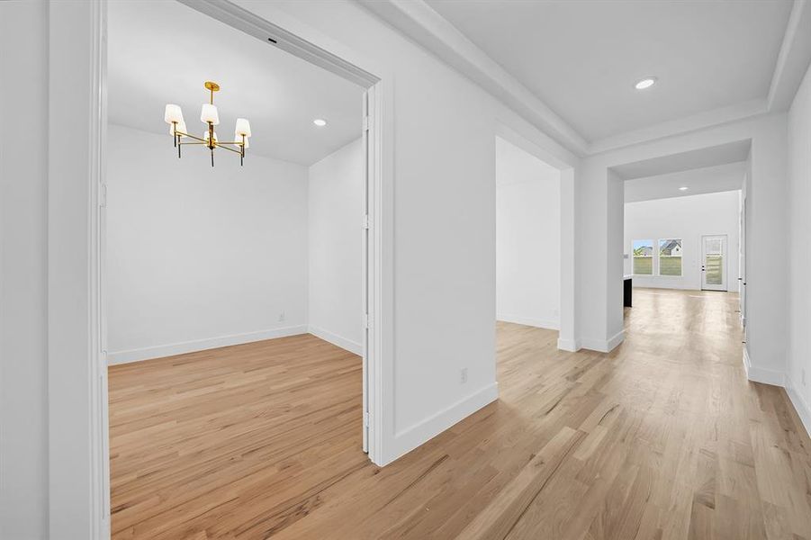 Hall featuring light wood-style floors, a chandelier, and recessed lighting