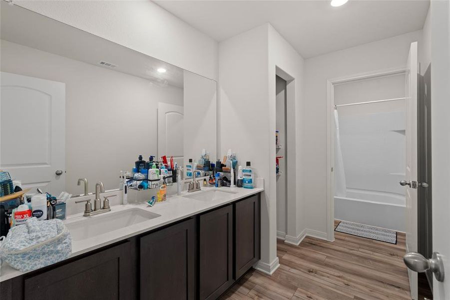 Full bathroom featuring double vanity, recessed lighting, light wood-style flooring, and shower / tub combo with curtain