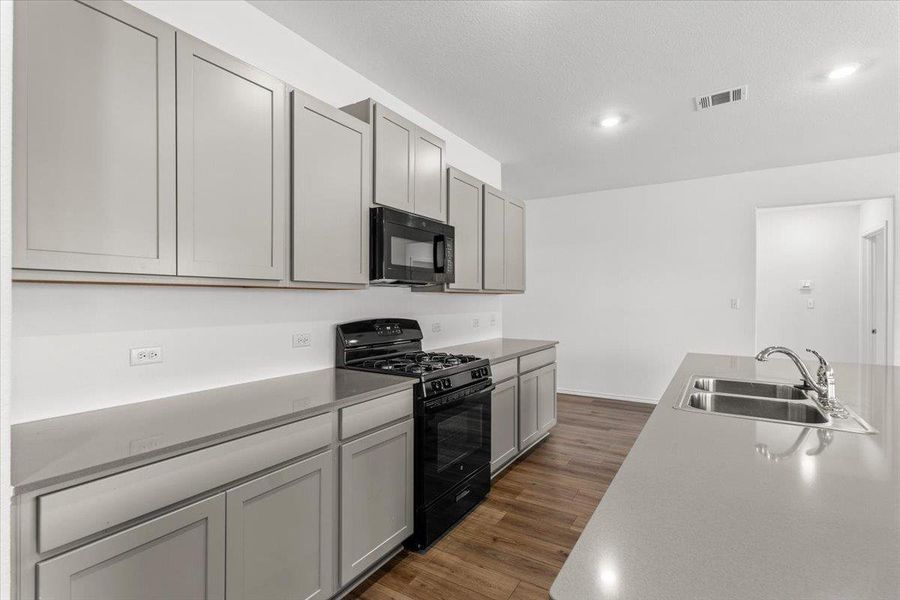 Kitchen with black appliances, gray cabinetry, dark wood-type flooring, and recessed lighting