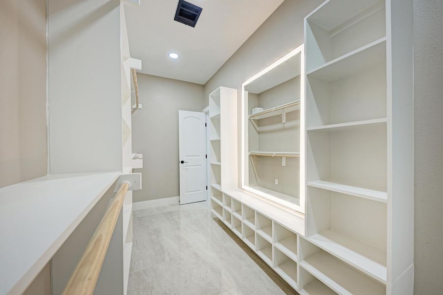 Abundant built-in shelving and tile flooring define this spacious closet organization system. Abundant built-in shelving and tile flooring define this spacious closet organization system.