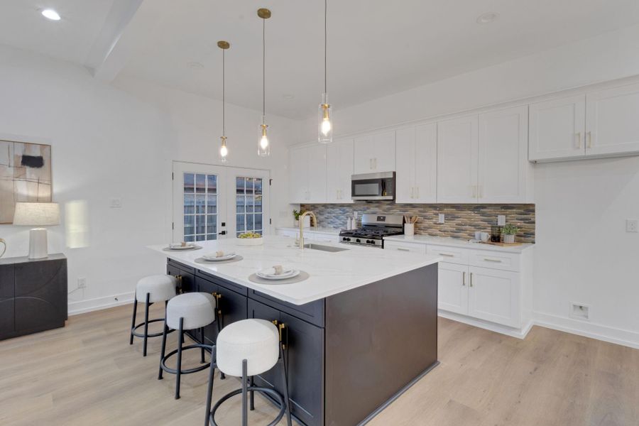 Gourmet kitchen featuring quartz countertops, stylish backsplash, and a large island with pendant lighting—perfect for entertaining. Gourmet kitchen featuring quartz countertops, stylish backsplash, and a large island with pendant lighting—perfect for entertaining.