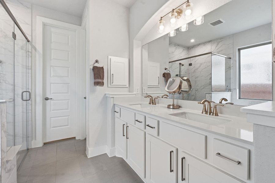 Full bathroom featuring double vanity and a marble finish shower