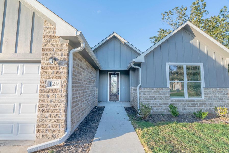View of exterior entry featuring board and batten siding, stone siding, and a garage View of exterior entry featuring board and batten siding, stone siding, and a garage