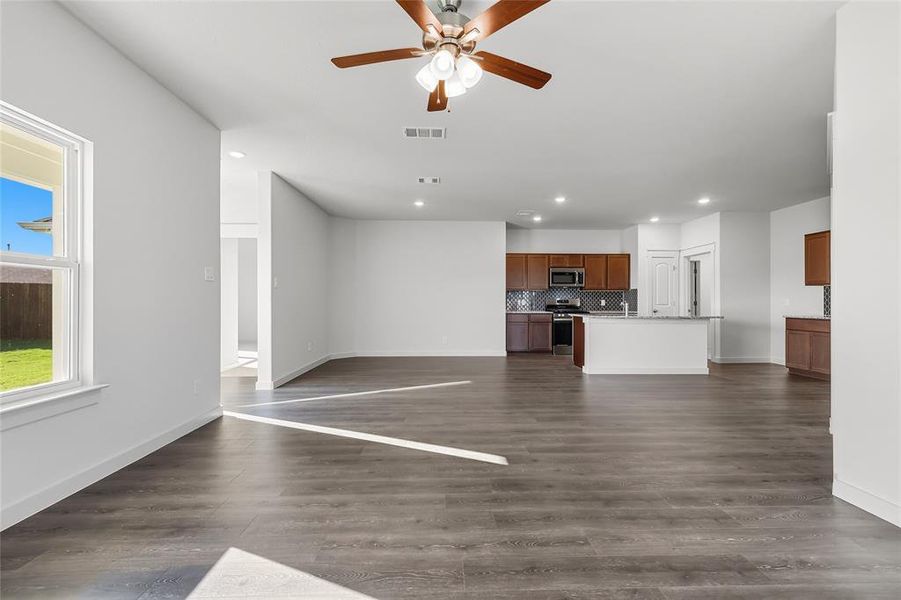 Unfurnished living room featuring dark wood-type flooring, ceiling fan, and recessed lighting Unfurnished living room featuring dark wood-type flooring, ceiling fan, and recessed lighting