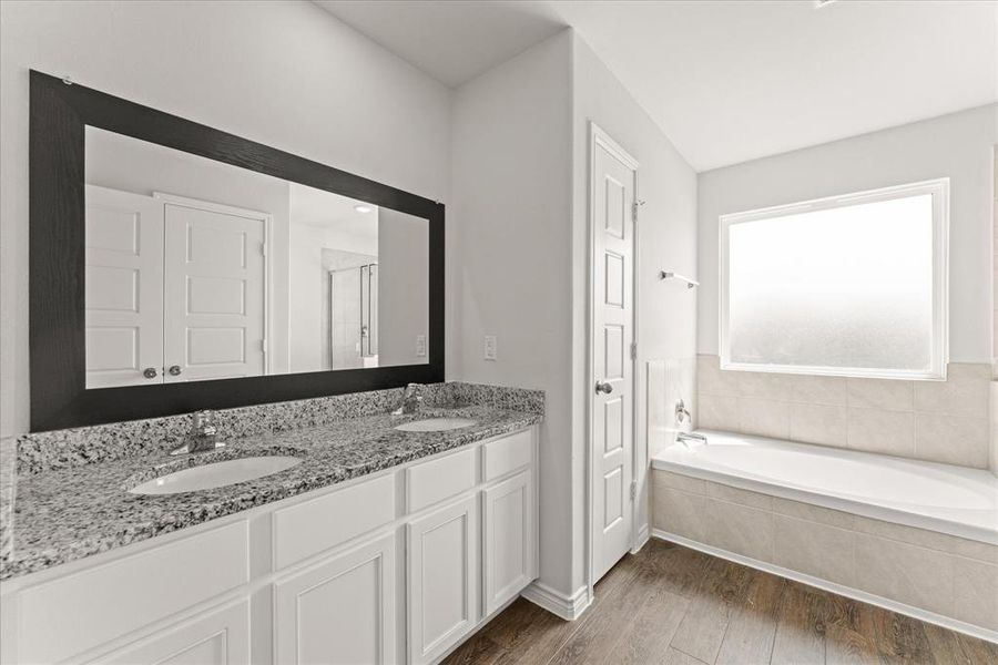Full bath with dark wood-style flooring, a garden tub, double vanity, and a shower stall Full bath with dark wood-style flooring, a garden tub, double vanity, and a shower stall