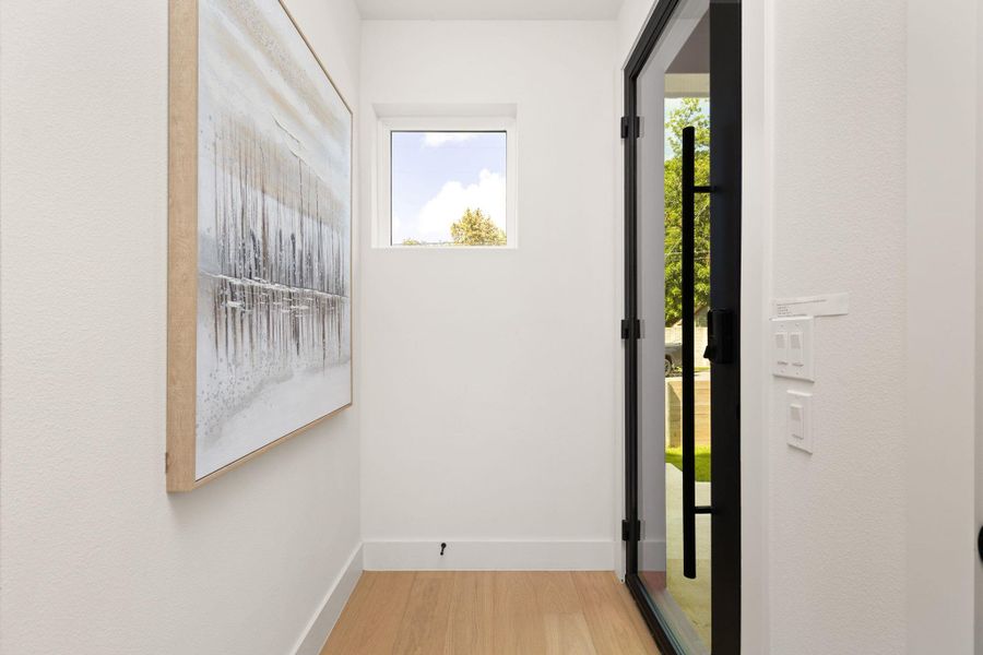 Enter a luminous hall featuring rich hardwood floors and an airy window. Enter a luminous hall featuring rich hardwood floors and an airy window.