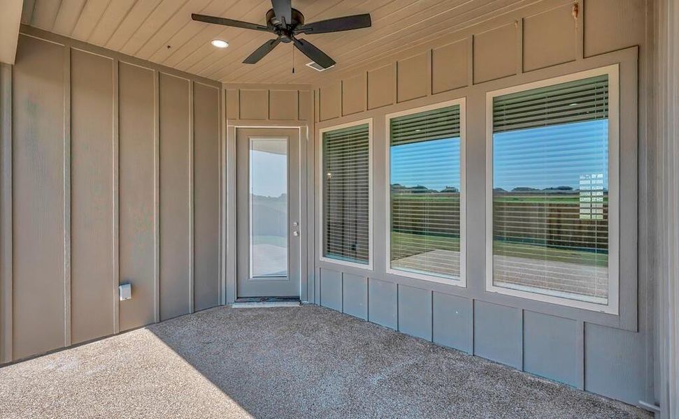 Doorway to property with board and batten siding, a patio area, and ceiling fan