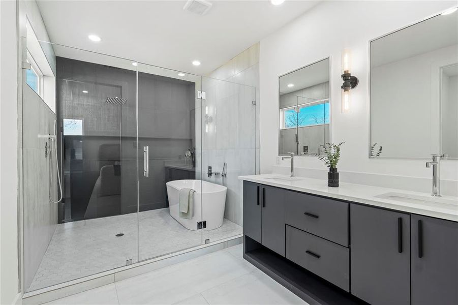 Bathroom with double vanity, a stall shower, a freestanding bath, and light tile patterned floors