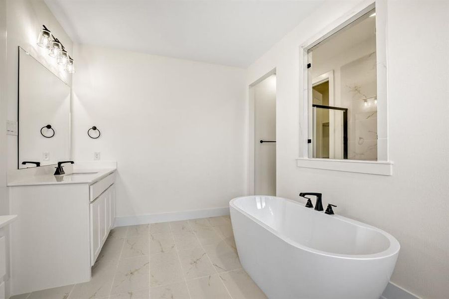 Bathroom featuring vanity, a freestanding bath, and light marble finish floors