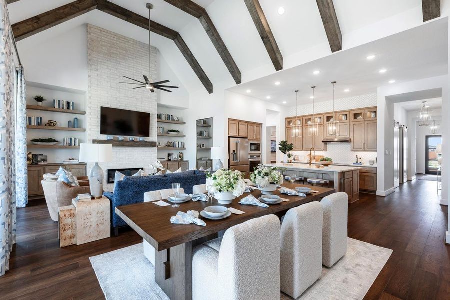 Dining area featuring high vaulted ceiling, beam ceiling, a ceiling fan, a fireplace, and dark wood-type flooring Dining area featuring high vaulted ceiling, beam ceiling, a ceiling fan, a fireplace, and dark wood-type flooring