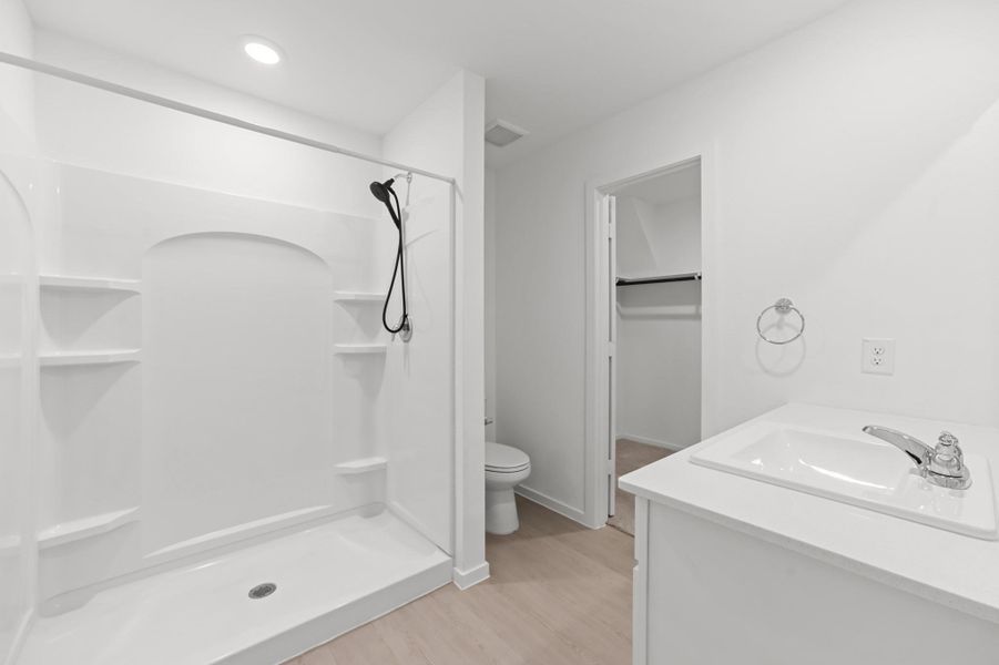 Bright primary bath features a spacious walk-in shower with built-in shelving, a streamlined vanity, and direct access to the walk-in closet. Bright primary bath features a spacious walk-in shower with built-in shelving, a streamlined vanity, and direct access to the walk-in closet.