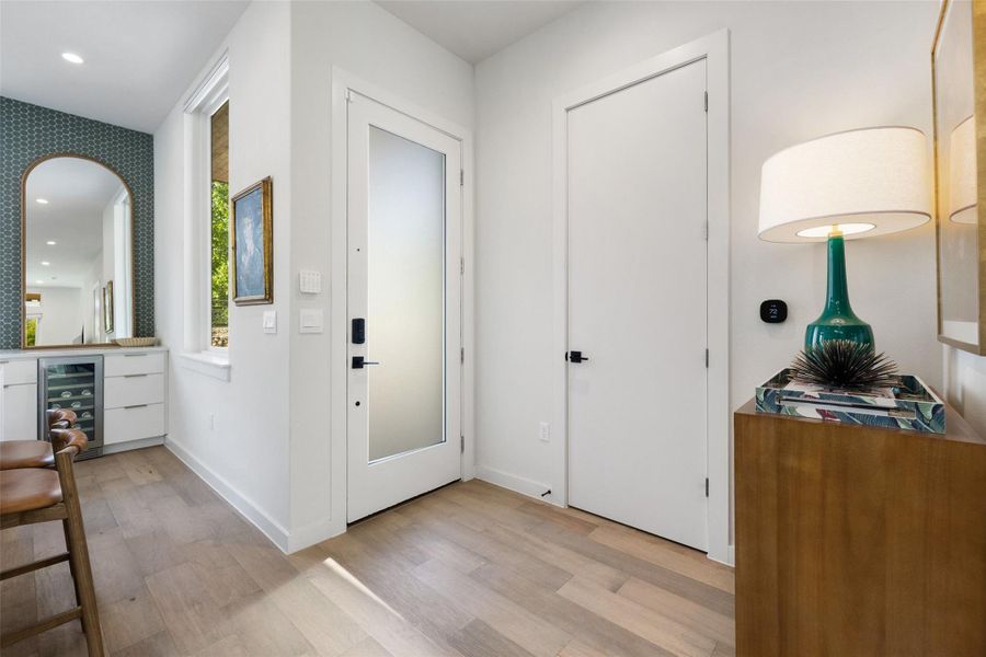 Foyer featuring recessed lighting, beverage cooler, light wood-style floors, arched walkways, and a dry bar