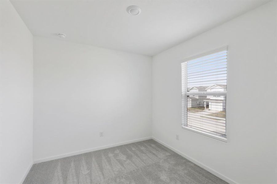 Bright room featuring a single window with horizontal blinds, light gray wall-to-wall carpeting, and recessed ceiling lighting