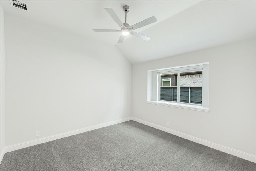 Empty bedroom with vaulted ceiling, ceiling fan, gray carpet, and single window Empty bedroom with vaulted ceiling, ceiling fan, gray carpet, and single window