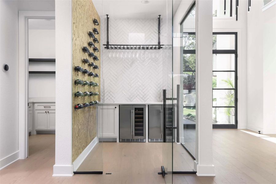 Dedicated beverage preparation area featuring a built-in wine rack, stemware holder, and two integrated beverage refrigerators