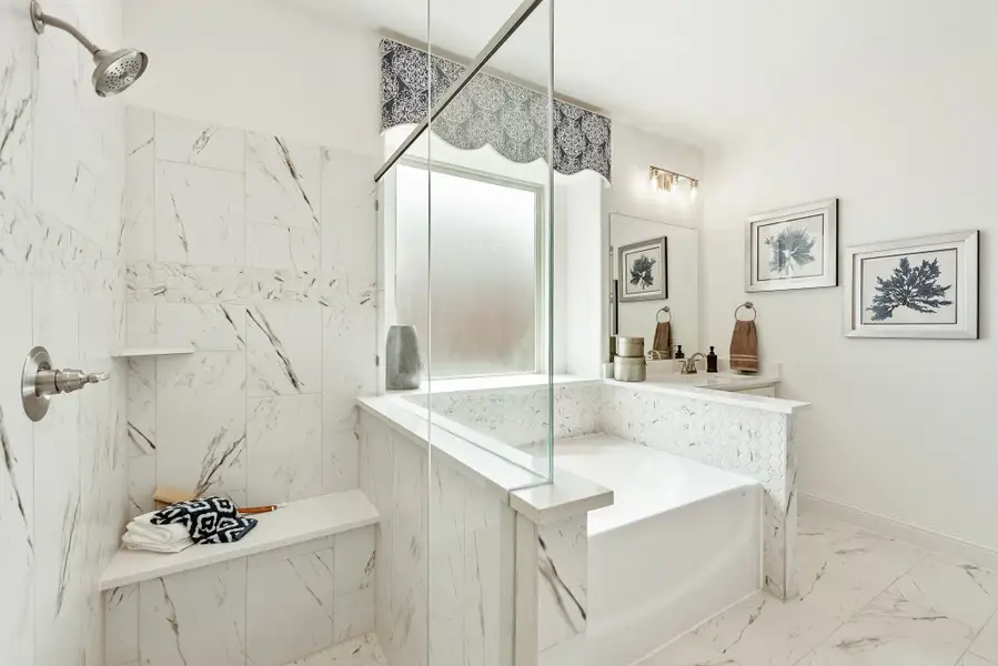 Bathroom with marble tile walk-in shower, built-in bench, and soaking tub with glass partition