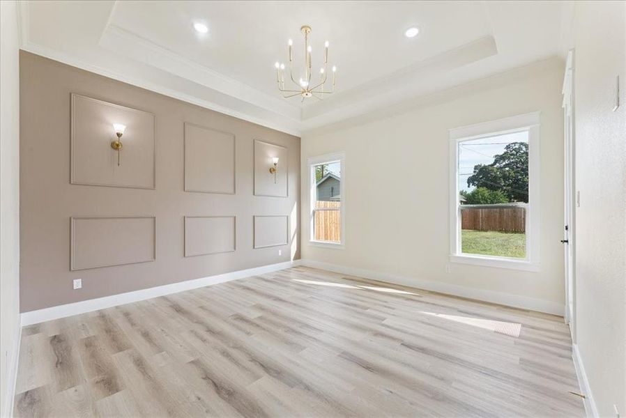 Foyer with a raised ceiling, a chandelier, light wood-style floors, crown molding, and recessed lighting