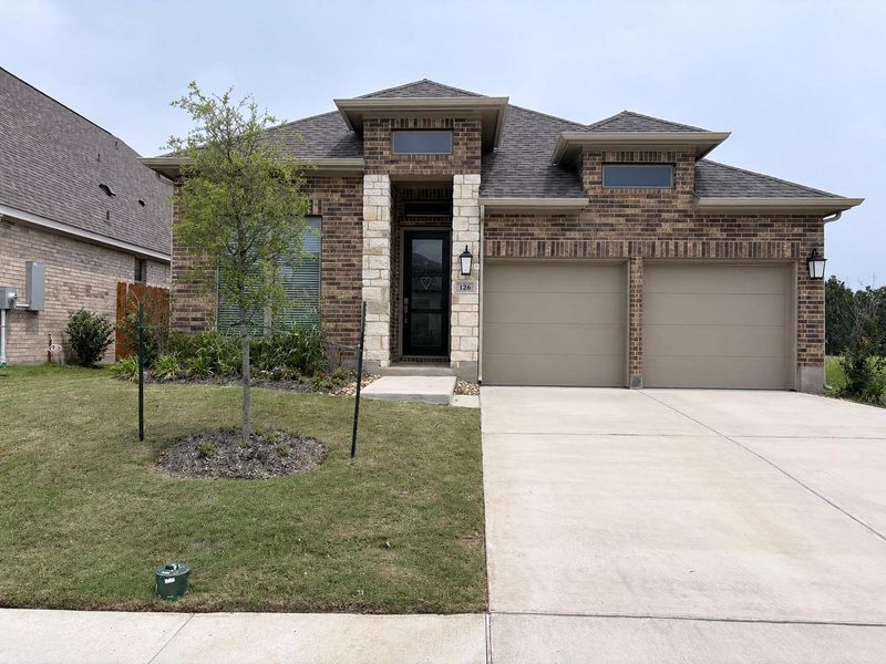 Brick and stone facade residence featuring a two-car garage, concrete driveway, and front landscaping Brick and stone facade residence featuring a two-car garage, concrete driveway, and front landscaping