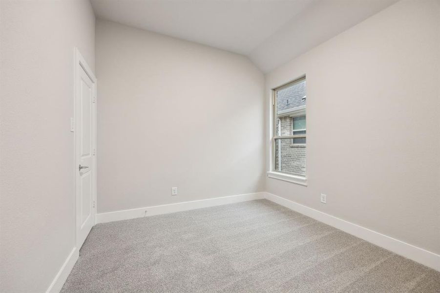 Carpeted empty room with vaulted ceiling