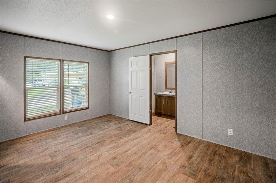 Unfurnished room featuring a decorative wall, ornamental molding, and light wood-style flooring
