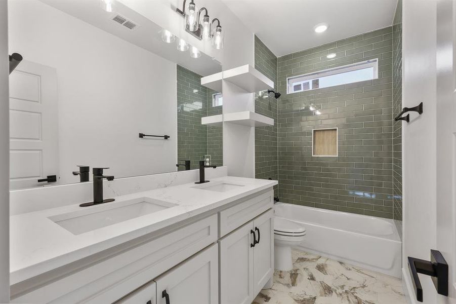 Full bathroom with tiled shower / bath combo, vanity, and toilet