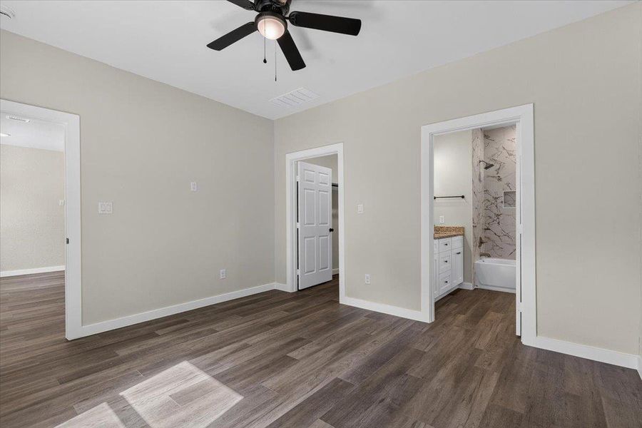 Plank flooring runs throughout this primary suite offering views into the adjoining bath. Plank flooring runs throughout this primary suite offering views into the adjoining bath.