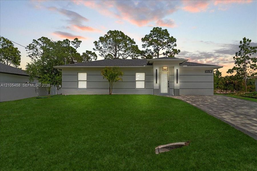 Modern exterior with horizontal siding, a paver driveway, and an established lawn Modern exterior with horizontal siding, a paver driveway, and an established lawn