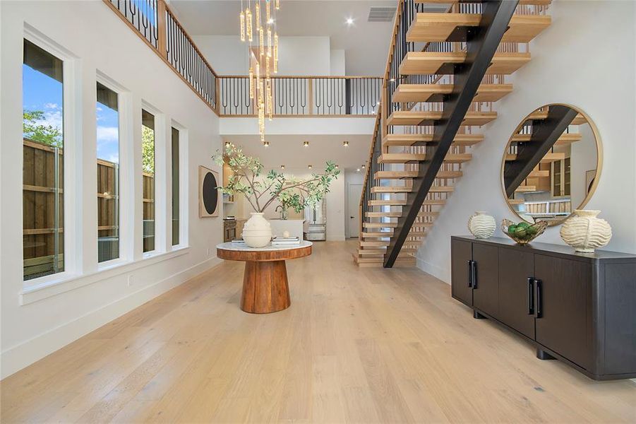 Foyer entrance with a chandelier, light wood-style floors, a high ceiling, and stairway Foyer entrance with a chandelier, light wood-style floors, a high ceiling, and stairway