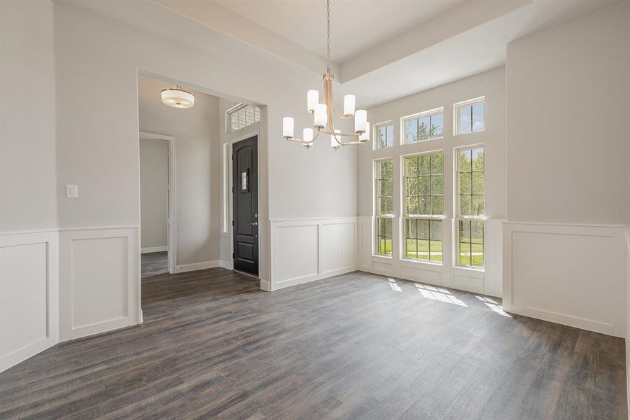 Unfurnished dining area with a healthy amount of sunlight, dark wood-type flooring, and a notable chandelier