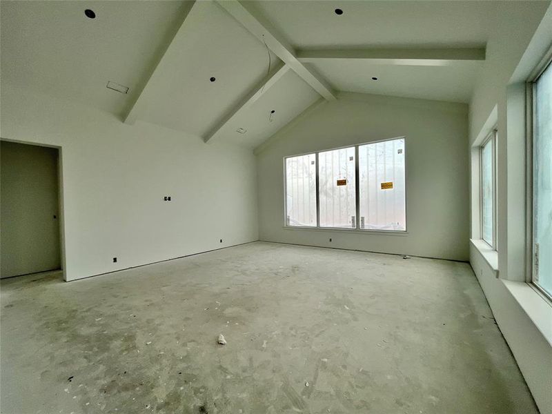 Empty room with vaulted ceiling with beams