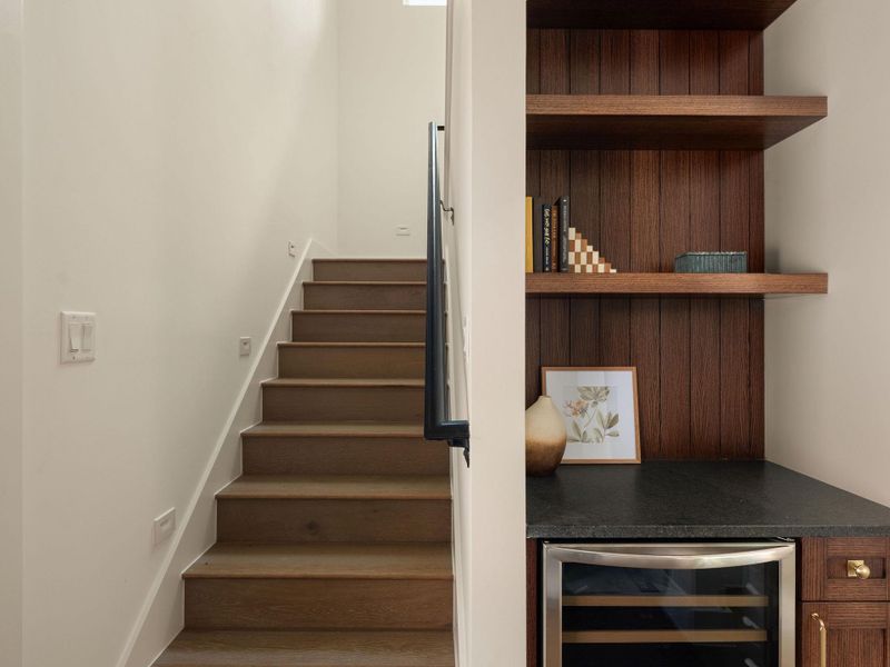 Elegant wooden staircase and built-in shelving with sleek countertops define a refined entryway.