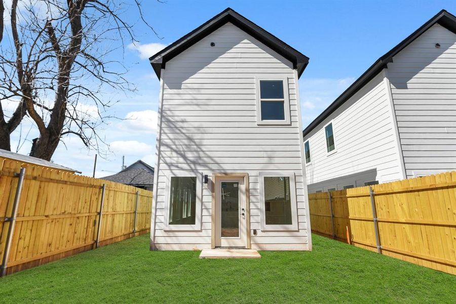 Rear view of property featuring a fenced backyard and a yard