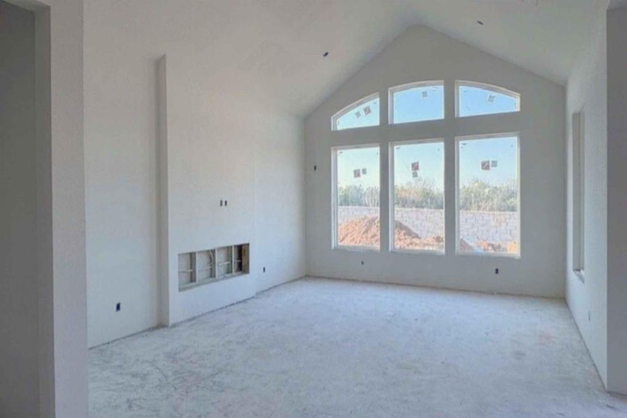 Unfurnished living room with a high ceiling, light colored carpet, and a fireplace