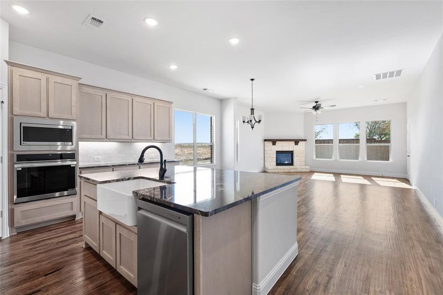 Kitchen with dark stone counters, healthy amount of natural light, appliances with stainless steel finishes, a kitchen island with sink, and recessed lighting