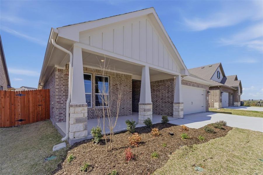 View of front of home with brick siding, board and batten siding, concrete driveway, an attached garage, and a porch