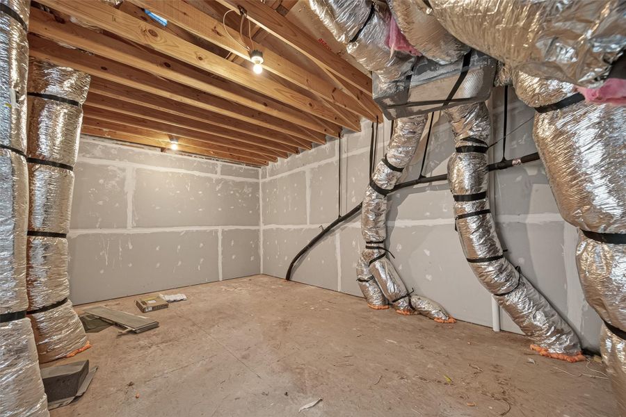 This photo shows an unfinished attic with visible ductwork and exposed wooden beams. The walls are partially drywalled, and the space is equipped with basic lighting, offering potential for customization or storage. This photo shows an unfinished attic with visible ductwork and exposed wooden beams. The walls are partially drywalled, and the space is equipped with basic lighting, offering potential for customization or storage.