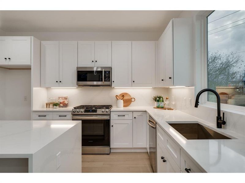 Equipped with brand new stainless steel appliances, an in-lay sink, and sleek black hardware, this kitchen combines top-of-the-line functionality with a refined aesthetic.