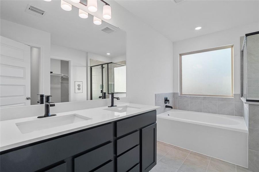 This primary bathroom is definitely move-in ready! Featuring an large soaking tub and walk-in shower with tile surround, dual vanity sinks, stained cabinets with light countertops, high ceilings, neutral paint, sleek and modern finishes.