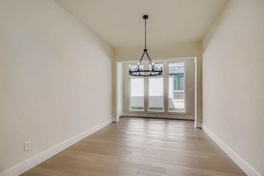 Unfurnished dining area with light wood finished floors and a chandelier