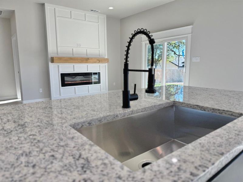 Kitchen with light stone countertops, white cabinetry, and sink