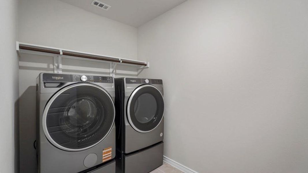 Dedicated laundry space with light gray walls, white baseboards, and a built-in hanging rod Dedicated laundry space with light gray walls, white baseboards, and a built-in hanging rod