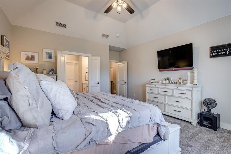 Carpeted bedroom with ceiling fan and lofted ceiling