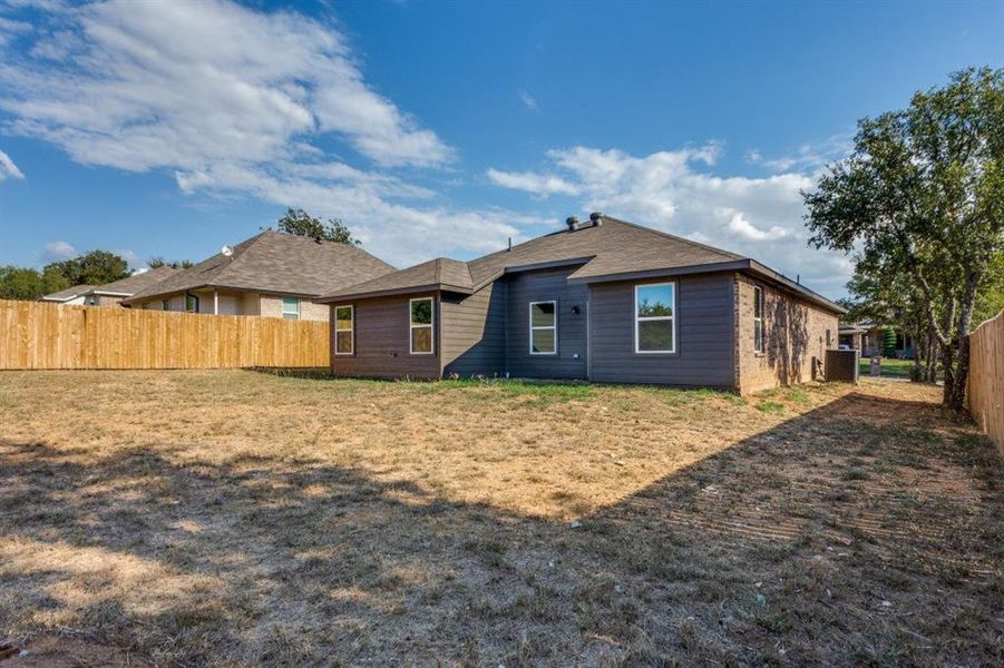 Rear view of property featuring a fenced backyard and roof with shingles