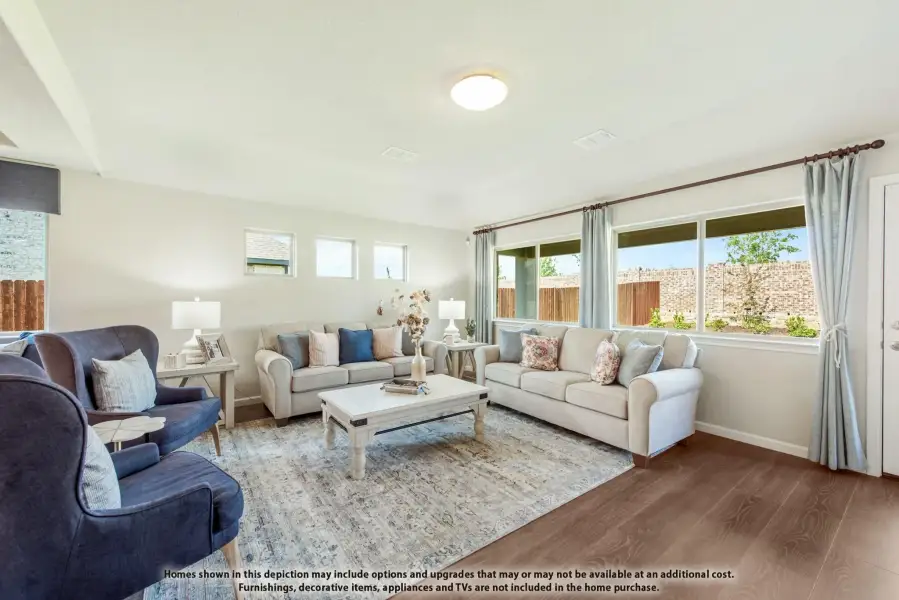 Living room with hardwood floors, two beige sofas, blue accent chairs, and large windows with natural light