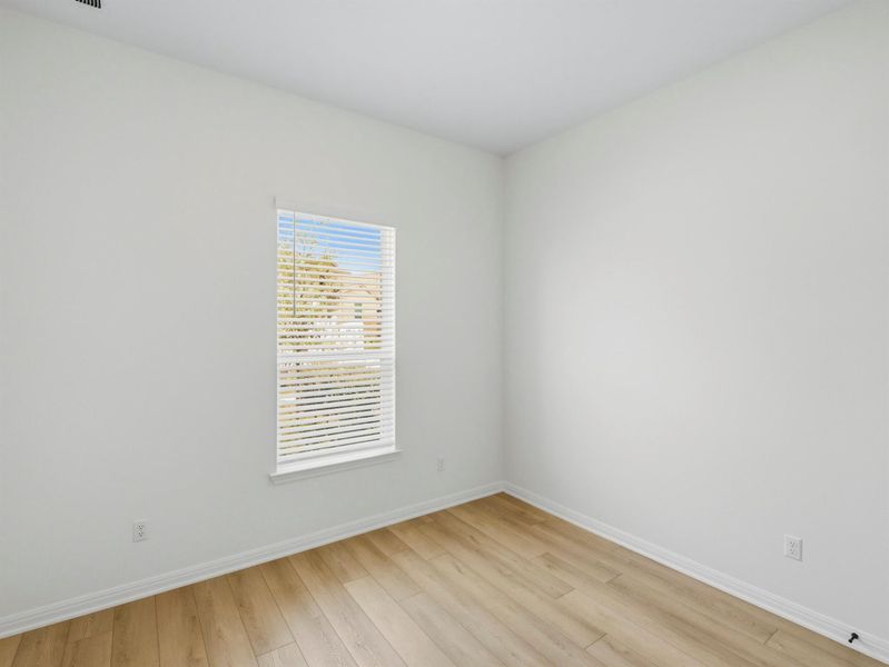 An inviting room features light wood-look flooring and a window with blinds, creating a versatile space. An inviting room features light wood-look flooring and a window with blinds, creating a versatile space.