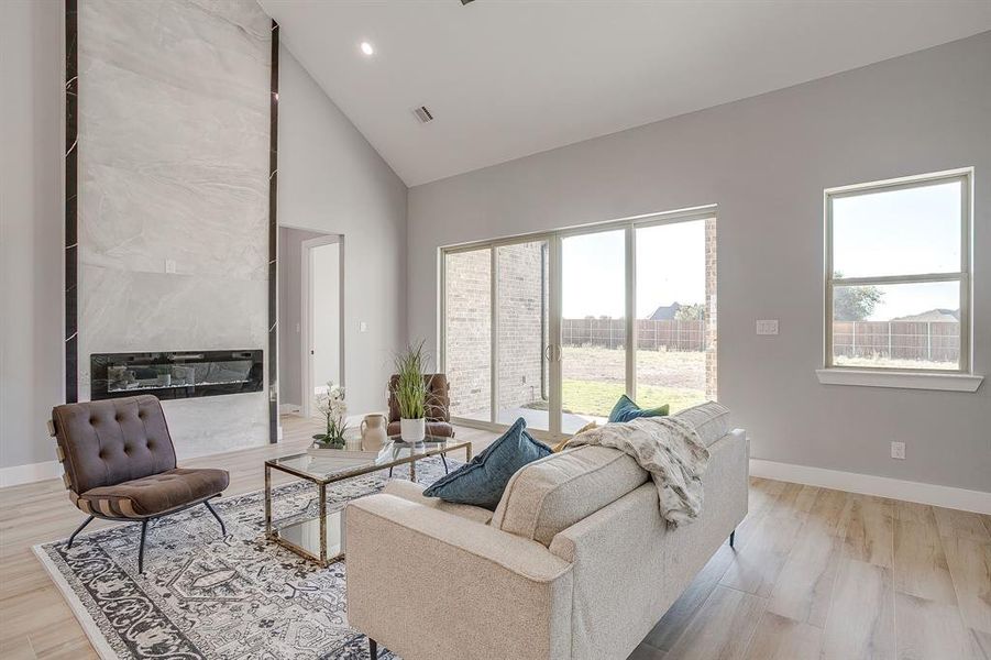 Living area featuring high vaulted ceiling, light wood finished floors, recessed lighting, and a high end fireplace